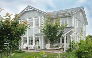 Luxurious two-story home with lush lawn and outdoor chairs.