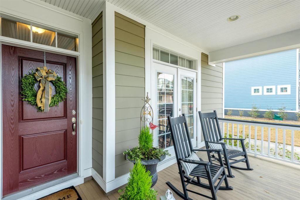 Front porch with plants and two rocking chairs.